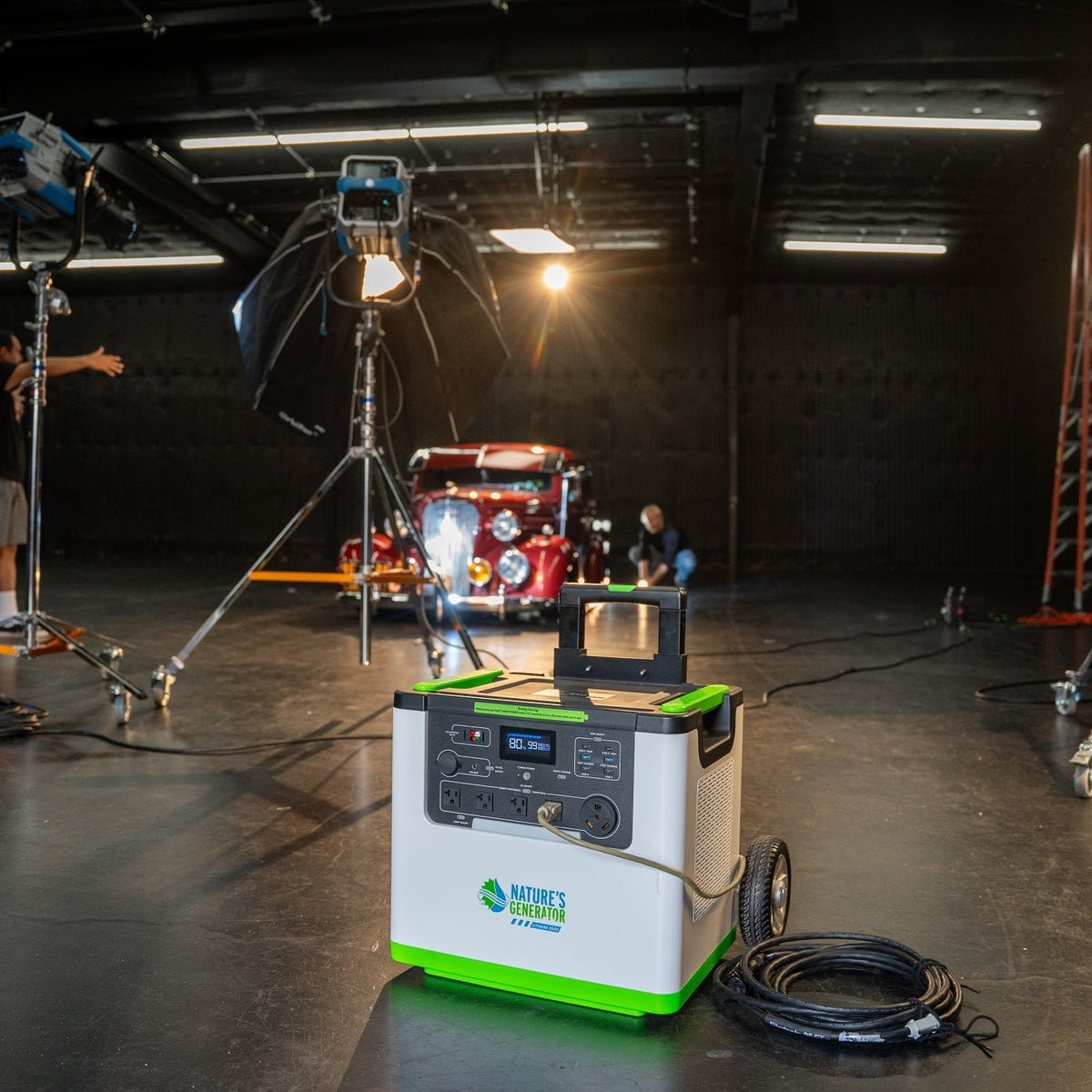 Portable power station with green and white design in a studio setting with filming equipment.